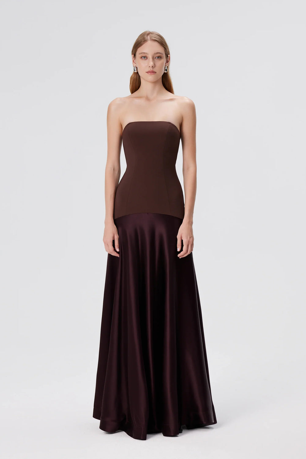 Woman wearing a strapless brown evening gown on a white background