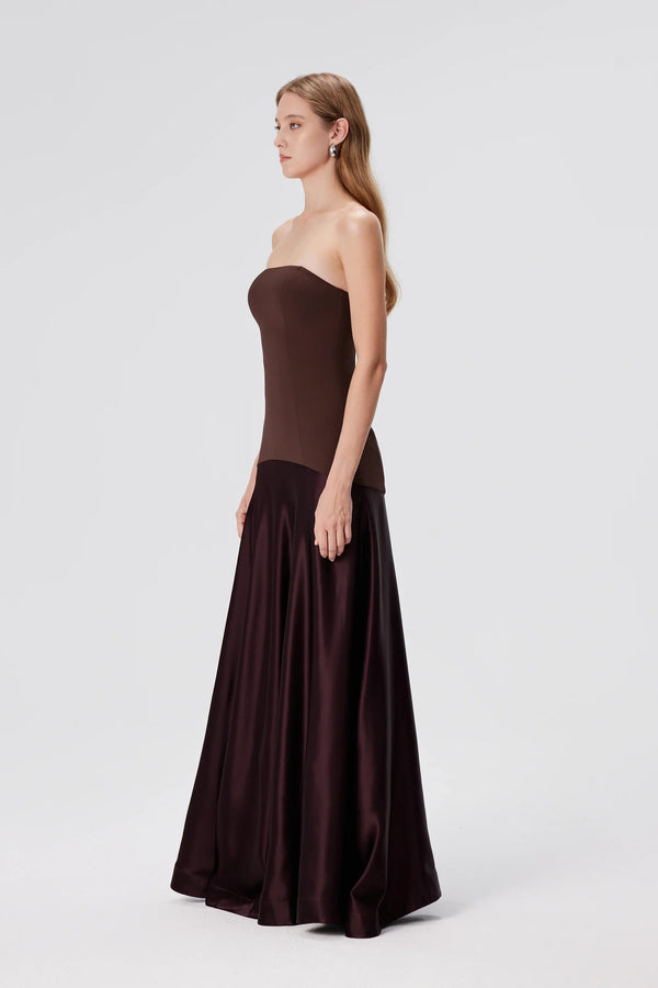 Woman wearing a strapless brown evening gown on a white background