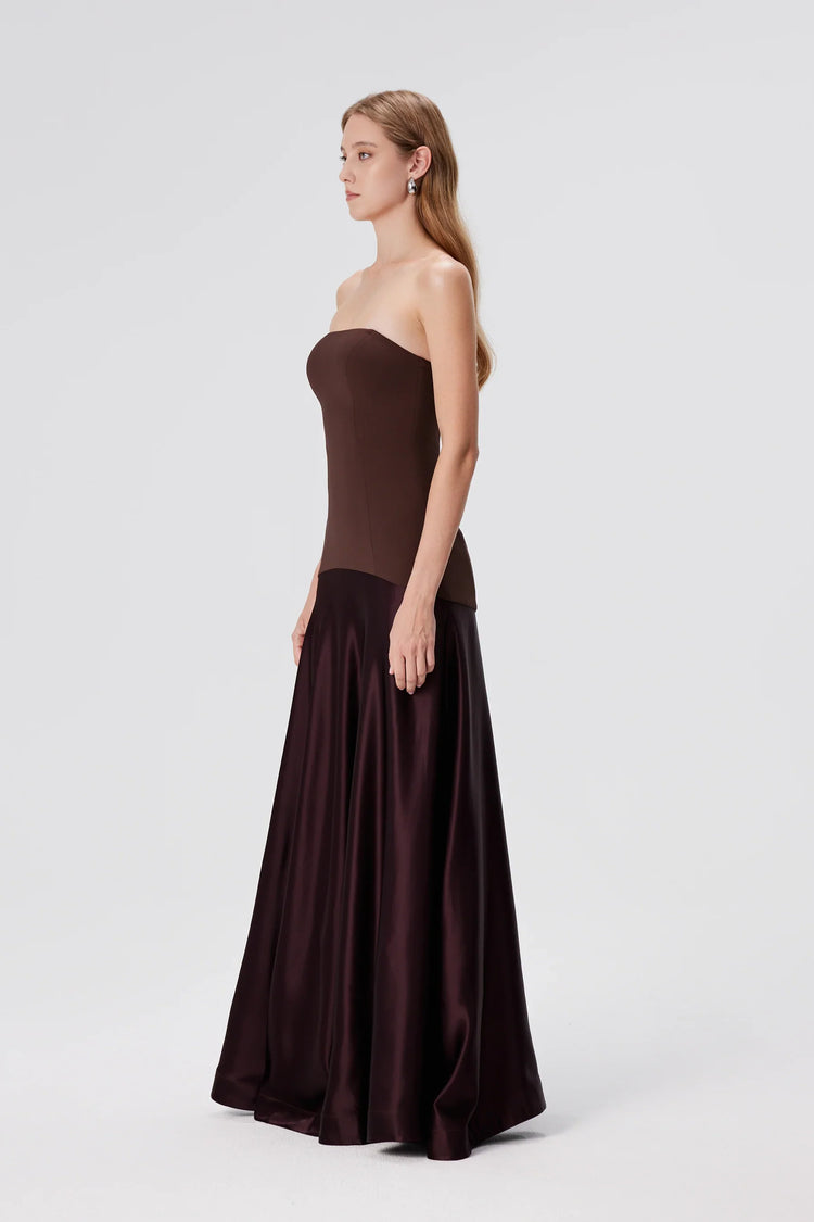 Woman wearing a strapless brown evening gown on a white background