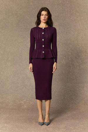 Woman wearing a purple peplum top and skirt against a brown background