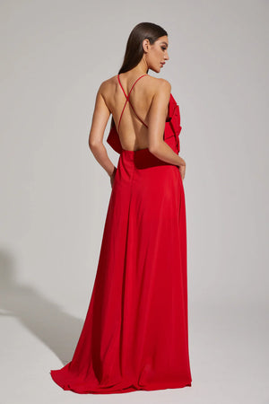 Woman wearing a red evening gown with an open back on a plain background