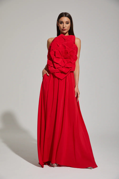 Woman wearing a red evening gown with floral details on a white background