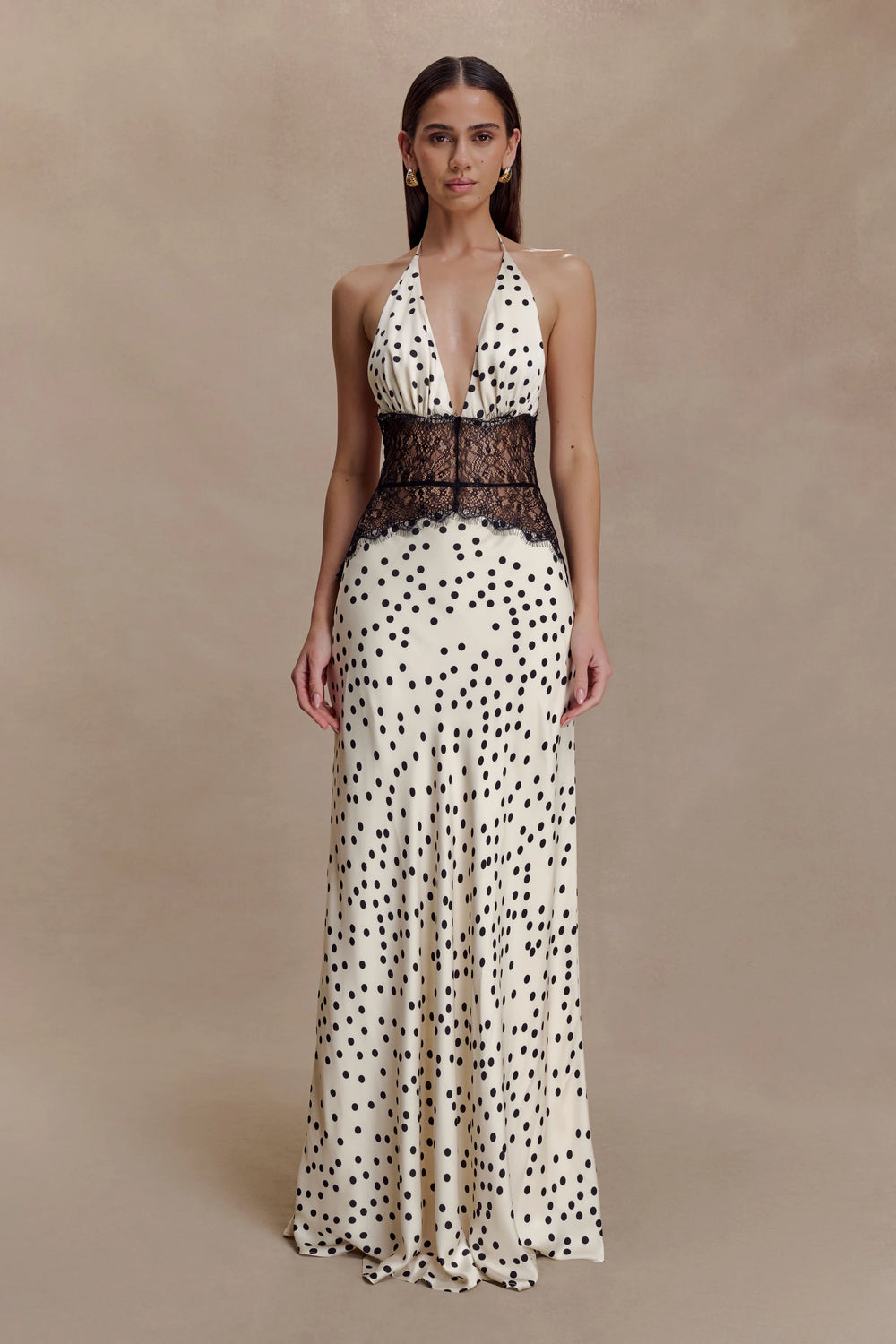 Woman wearing a polka dot dress with a lace bodice on a beige background