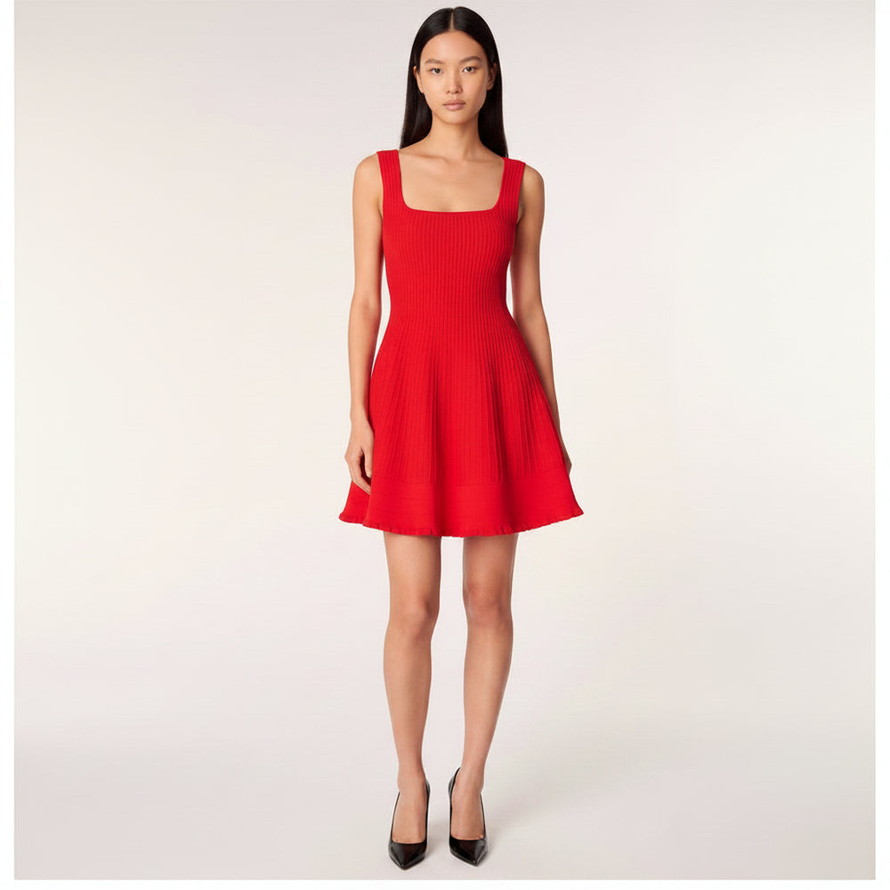 A model wearing a bright red ribbed knit sleeveless dress with a square neckline, wide shoulder straps, and a flared skirt with pockets, set against a plain light gray studio background.