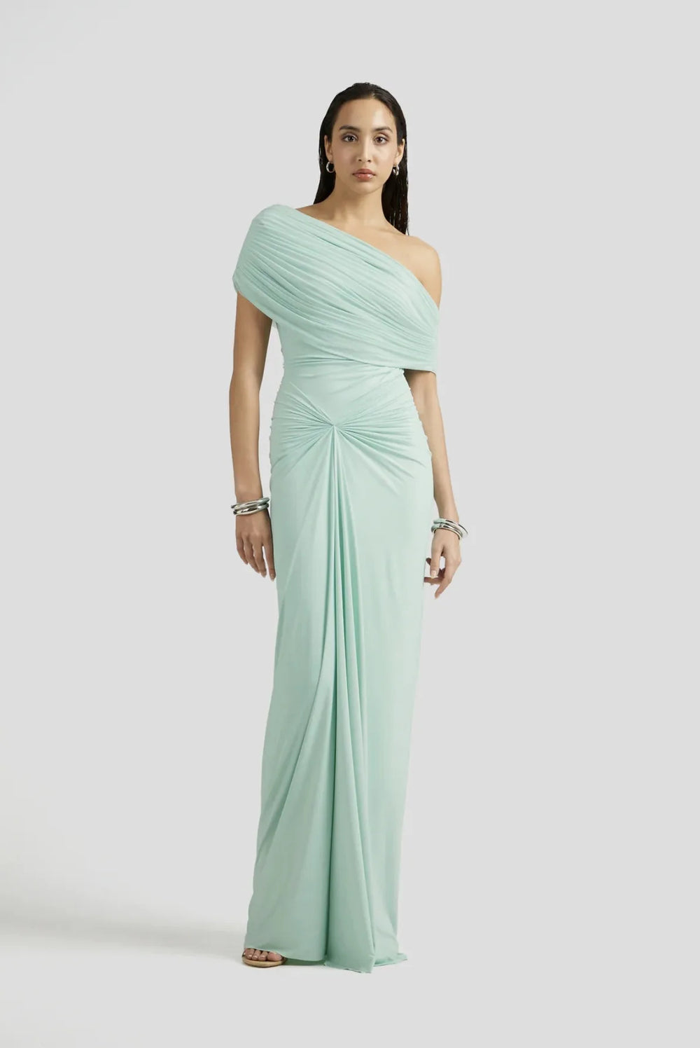 Woman wearing a light green one-shoulder dress on a white background