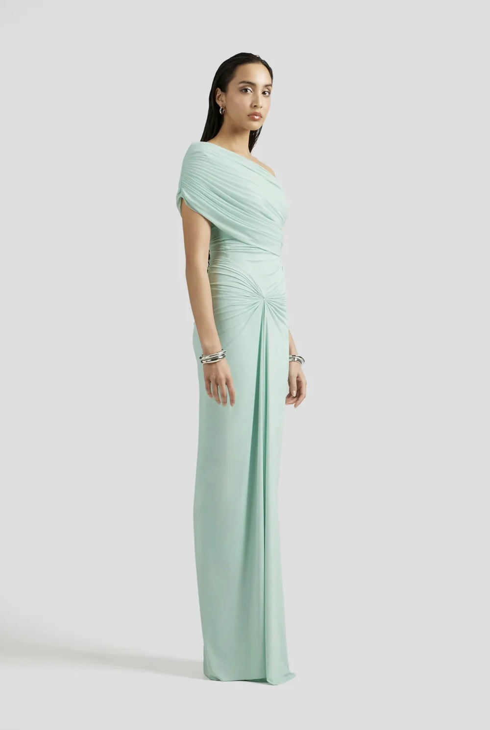 Woman wearing a light green one-shoulder dress on a white background