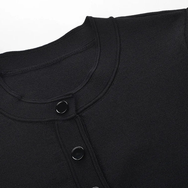 Close-up of a black garment with buttons on a white background