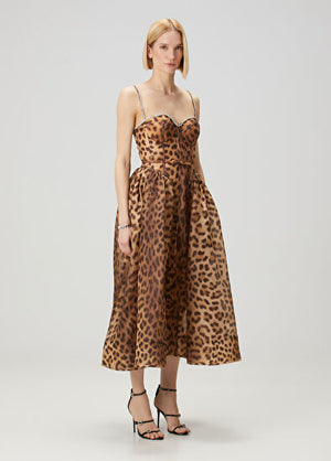 Woman wearing a leopard print dress on a plain background