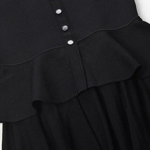 Black dress with ruffled details and buttons on a white background