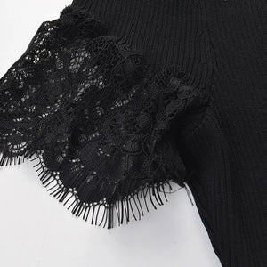 Close-up of a black ribbed knit garment with a wide black lace ruffle and fringe trim on a plain white background.