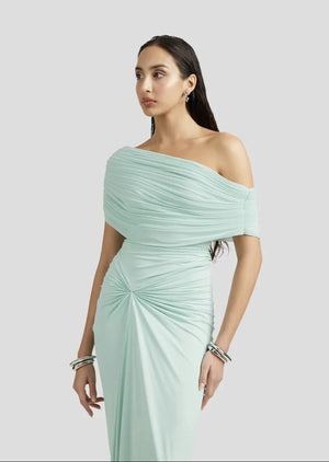 Woman wearing a light green off-shoulder dress on a plain background