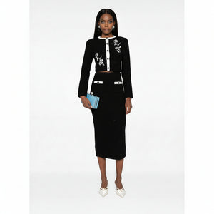 Woman wearing a black outfit with floral embroidery on a white background
