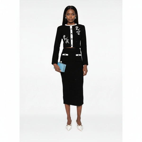Woman wearing a black outfit with floral embroidery on a white background