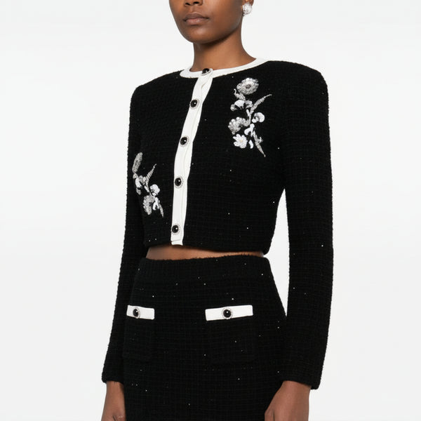 Black embroidered outfit with white buttons on a white background