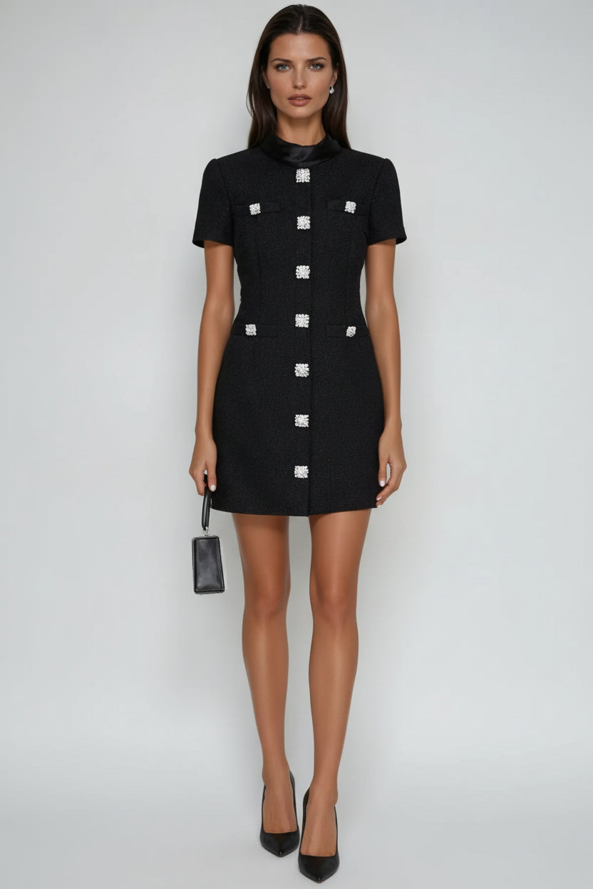 Woman wearing a black dress with silver buttons on a white background