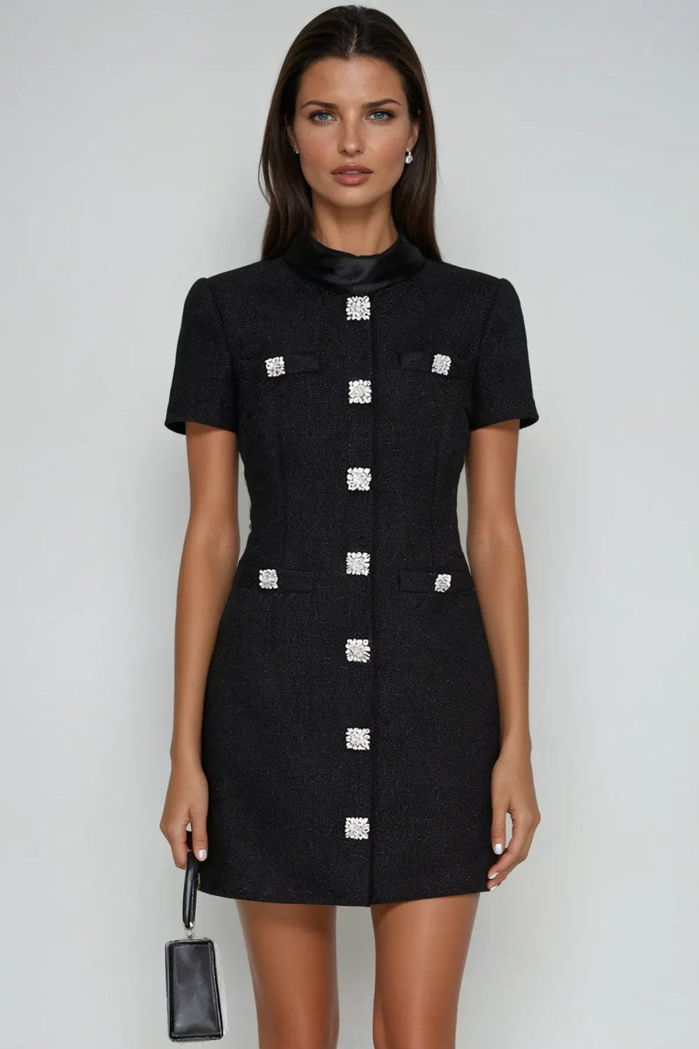 Woman wearing a black dress with silver buttons on a white background