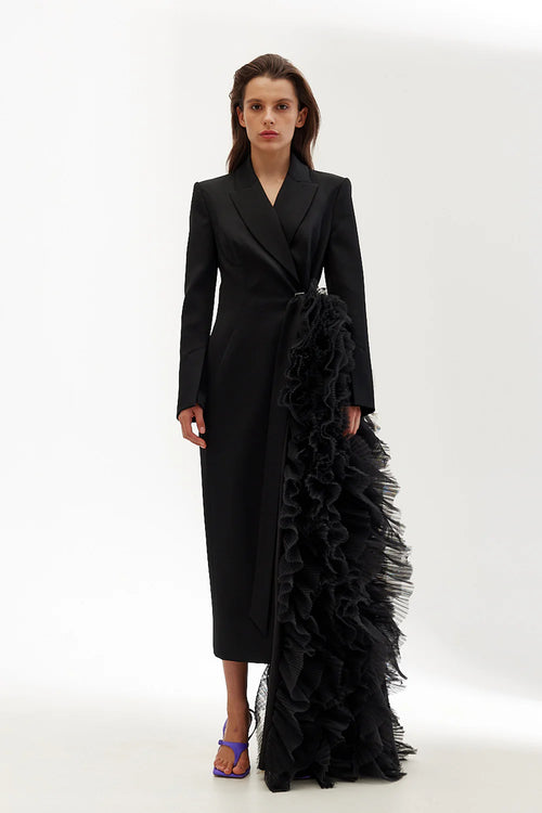 Woman wearing a black coat with ruffled details on a white background