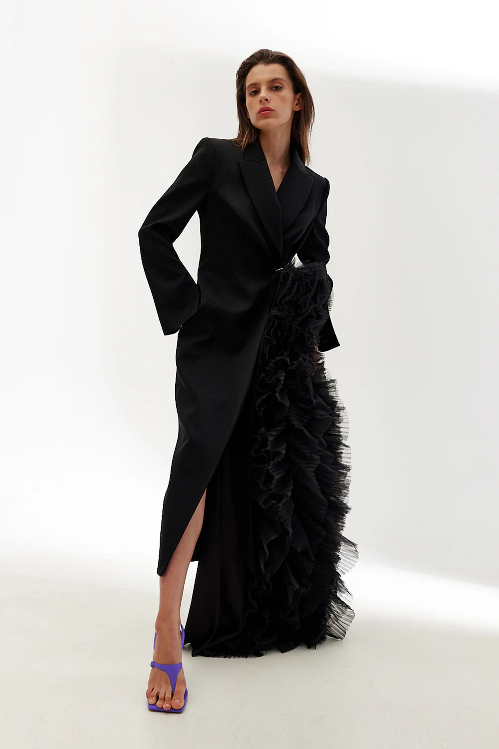 Woman wearing a black coat with ruffled details on a white background