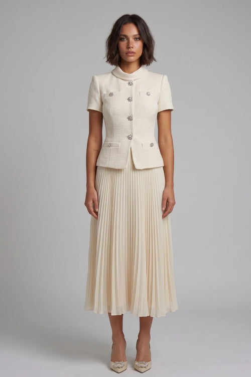 Woman wearing a cream-colored suit with a pleated skirt on a gray background