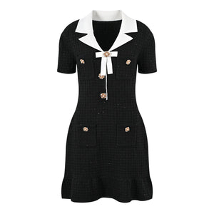 Black dress with white collar and gold buttons on a white background