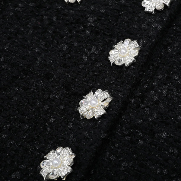 Pearl and crystal flower-shaped jewelry on a black fabric background