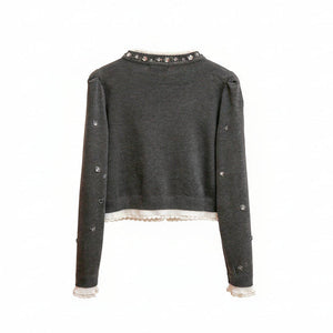 Dark gray sweater with decorative elements on a wooden hanger against a neutral background