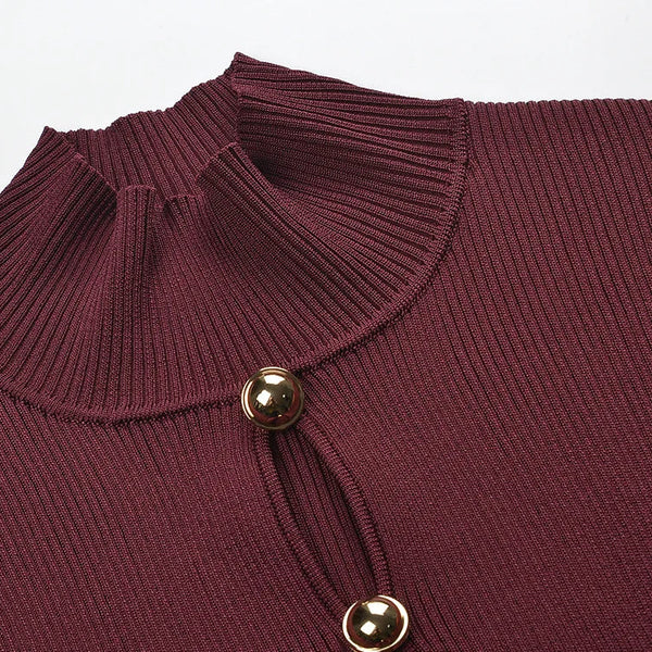 Close-up of a maroon ribbed sweater with gold buttons on a light gray background