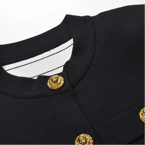 Close-up of a black outfit with gold buttons on a light gray background