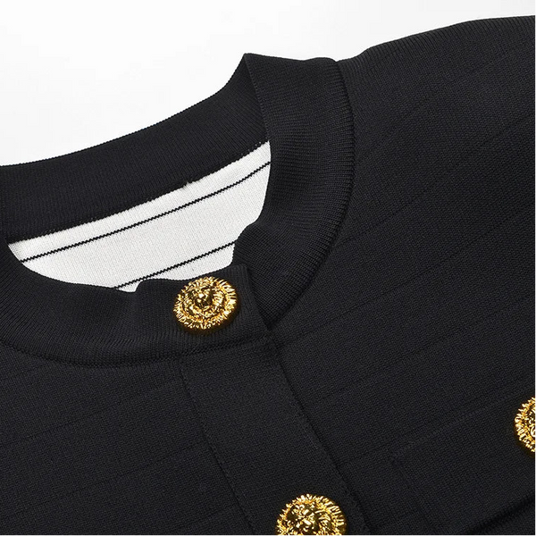 Close-up of a black outfit with gold buttons on a light gray background