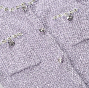 Close-up of a lavender textured fabric with decorative buttons and embellishments.