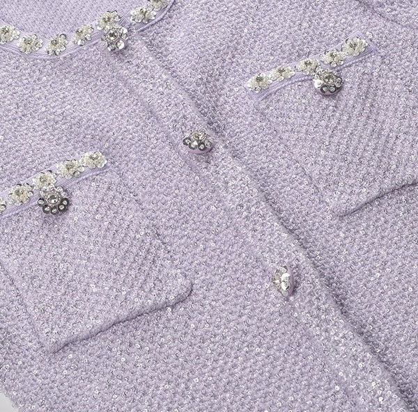 Close-up of a lavender textured fabric with decorative buttons and embellishments.