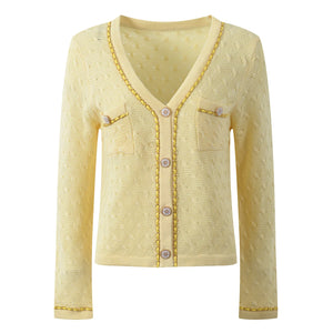 Yellow knitted cardigan with decorative buttons on a white background