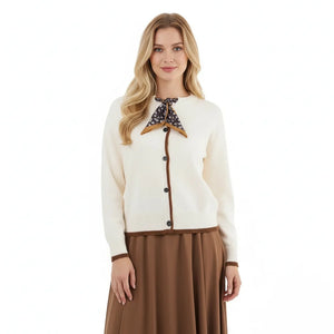 Woman wearing a cream cardigan with brown accents and a brown skirt on a white background