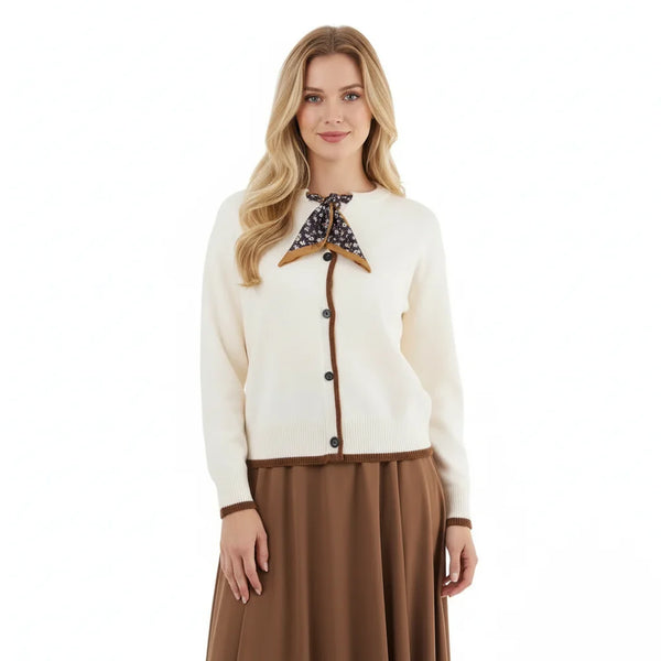 Woman wearing a cream cardigan with brown accents and a brown skirt on a white background