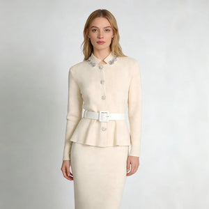 Woman wearing a cream-colored suit with a white belt on a light gray background