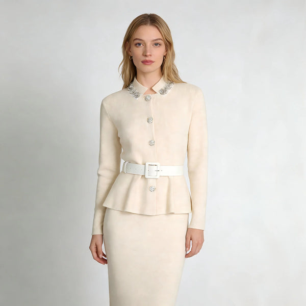 Woman wearing a cream-colored suit with a white belt on a light gray background