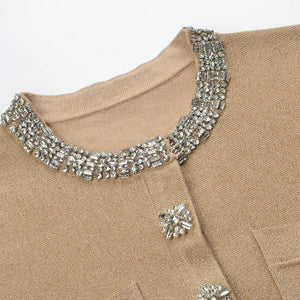 Close-up of a beige garment with a decorative silver collar and embellishments.