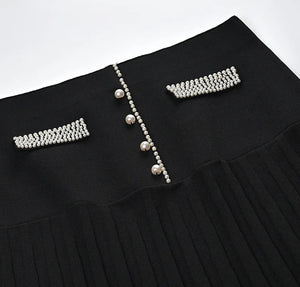 Black pleated skirt with pearl embellishments on a white background