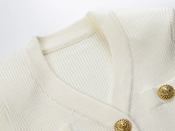 Close-up of a cream-colored sweater with gold buttons on a white background
