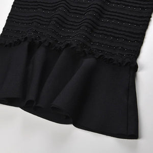 Black dress with textured top and ruffled skirt on a white background