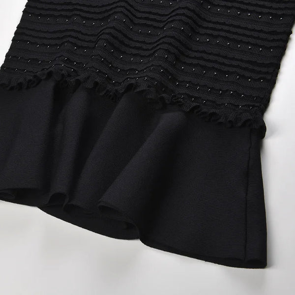 Black dress with textured top and ruffled skirt on a white background