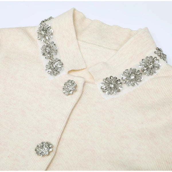 Cream-colored garment with decorative silver brooches on a white background
