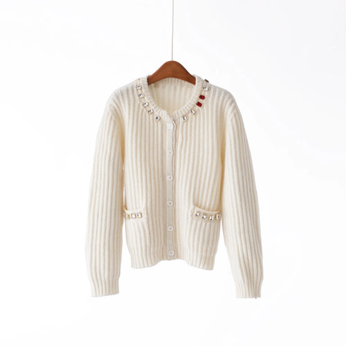 White ribbed knit cardigan with decorative buttons on a wooden hanger against a white background