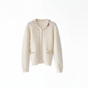 White ribbed knit cardigan with decorative buttons on a wooden hanger against a white background