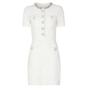 White dress with decorative buttons and embellishments on a white background