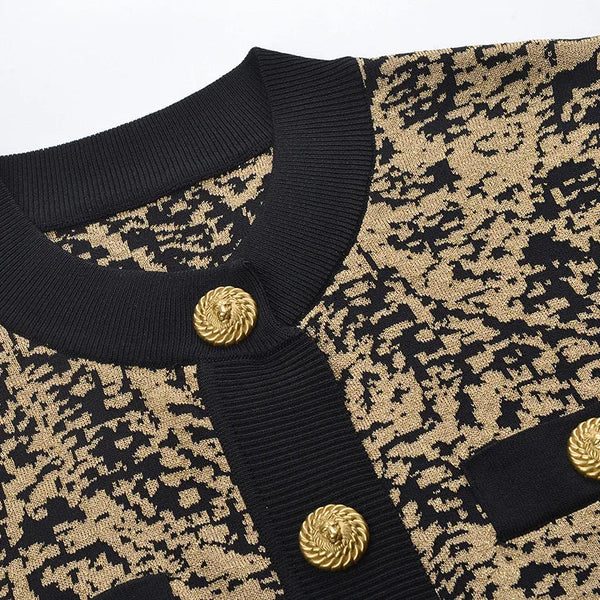 Close-up of a patterned garment with black and gold buttons on a light gray background