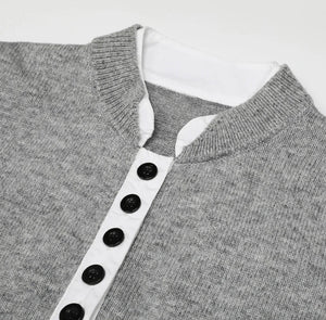 Gray sweater with a white collar and black buttons on a light gray background