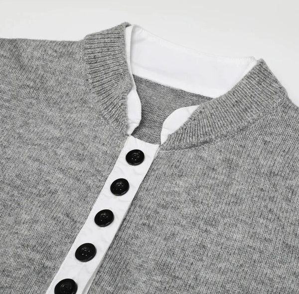 Gray sweater with a white collar and black buttons on a light gray background