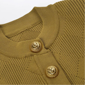 Close-up of a green sweater with gold buttons on a light gray background