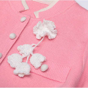 Close-up of a pink cardigan with white floral embroidery and buttons.